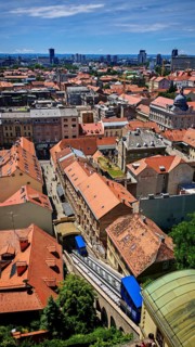 Panoramic view from Lotrscak Tower of an urban landscape with red roofs and a cable car going down