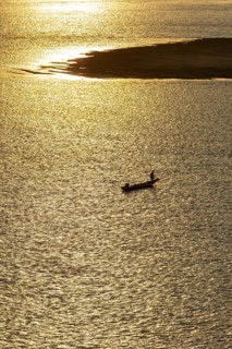 Fisherman with longtail boat (Thai: Ruea Hang Yao) at sunrise, Mekong between Thailand and Laos