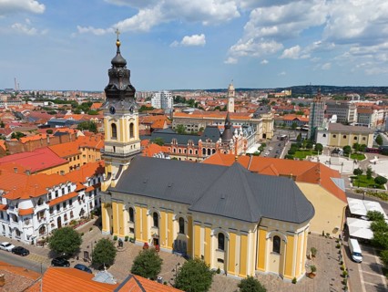 Baroque church with red roofs in the midst of an urban landscape, surrounded by cloudy sky, aerial