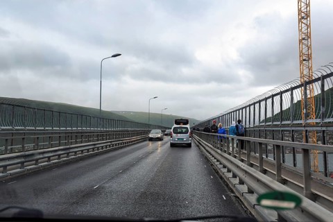 Car and passers-by on a bridge looking through a windshield in rainy weather, Tromso, Troms og