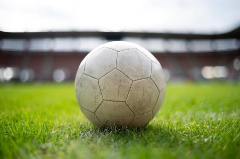 White soccer ball lying on the grass at stadium in Lubin, Poland