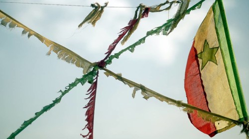 A frayed flag of Senegal, flag blowing in the wind against a blue sky, Casamance, Senegal