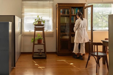 Rear view of a young female scientist in white lab coat standing in front of an open antique wooden