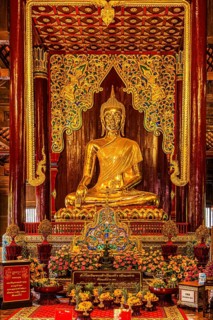 Gilded seated Buddha figure in a public prayer room, Wat Phra Singh Buddhist temple complex, Old