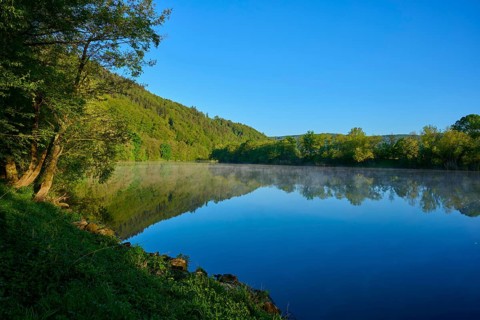 Wooded slopes are reflected in a quiet river on a clear morning, Boxtal, Main-Boxtal, Tauber-Kreis,