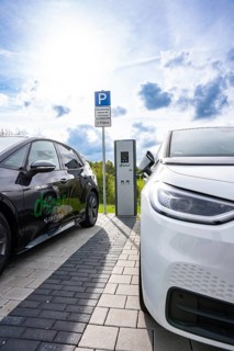 Two electric cars at a charging station in sunny weather with clouds in the sky, Deer charging