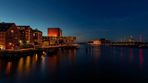 Abendstimmung in einer Stadt mit beleuchteten Gebäuden, die sich im Wasser spiegeln, Kopenhagen,