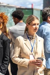 Young business professional attending an outdoor corporate conference, holding a coffee cup and