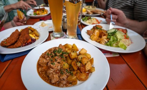 Table with drinks and Franconian dishes in a garden community, beef goulash with fried potatoes in