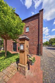 Historic water pump, flower pot, brick building, sidewalk, roads, pavers, paving stones, trees,
