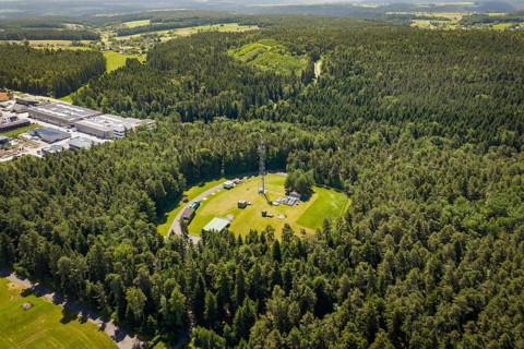 Extensive view of a radio tower in the center of a large wooded area under clear skies, Bunker