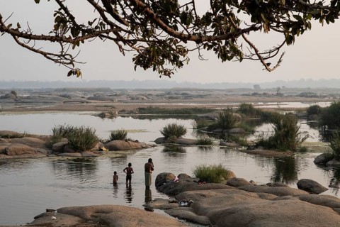 A father and his sons are bathing in the Mahanadi river in the wee hours (Odisha, India), in winter