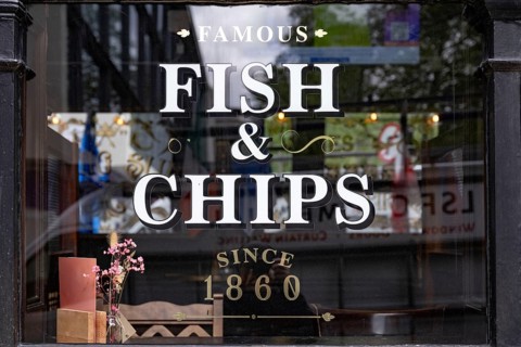A British pub window advertising Fish and Chips the most famous English dish found all over the UK