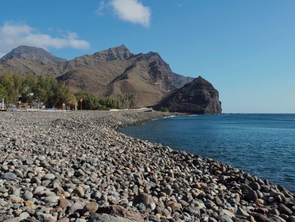 Pebble beach by the sea with mountains in the background on a sunny day, La Aldea de San Nicolas