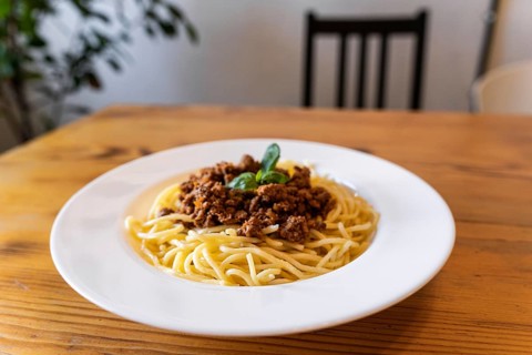Plate with traditional Italian pasta spaghetti bolognese on a wooden table in the restaurant
