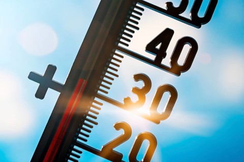 Thermometer in front of bright sun shows temperatures of around 30 degrees Celsius, symbolic photo