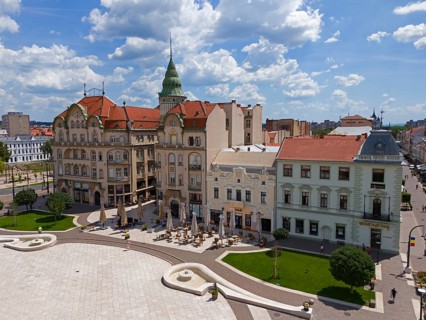 Historic buildings with red roofs and architectural details dominating an urban square, aerial