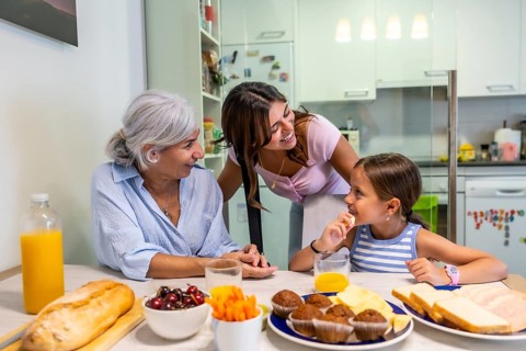 Multigenerational family members sharing a morning meal together, eating and talking around a