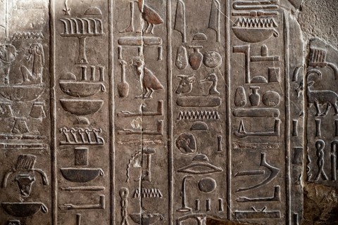 A closeup detail shot of stone carvings of Egyptian hieroglyphs in the Temple of Hatshepsut, Luxor.