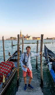 Young man at a boat dock for Venetian gondolas in St. Mark's Square, tourist enjoying the evening,