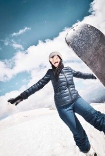 Happy excited cool caucasian brunette woman with skies pose in winter outfit in mountains. Copy