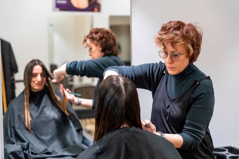 Stylist carefully trimming a young woman's hair in a modern hair salon, focusing on precision and