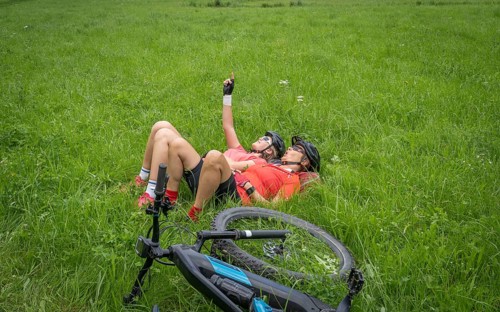Grandmother and granddaughter having a break in a green meadow during a mountain bike tour in upper