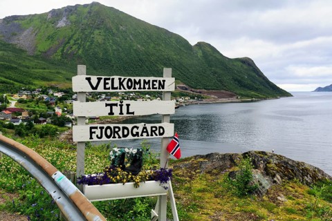 Town entrance sign to the small fishing village of Fjordgård, inscription Welcome, coastline on the