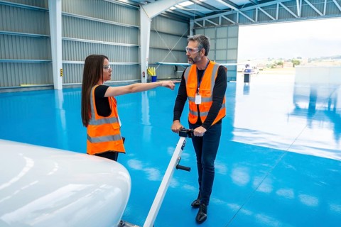 Aviation professionals wearing safety vests and goggles collaborating and communicating inside an