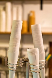 White paper cone cups arranged in multiple stacks within a shining metal dispenser stand, ready for