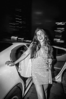 Young elegant woman in a shimmering sequin dress holding a champagne glass, stepping out of a