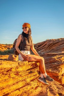 Young woman sitting on sandstone rock capturing the beauty of the arizona desert landscape,