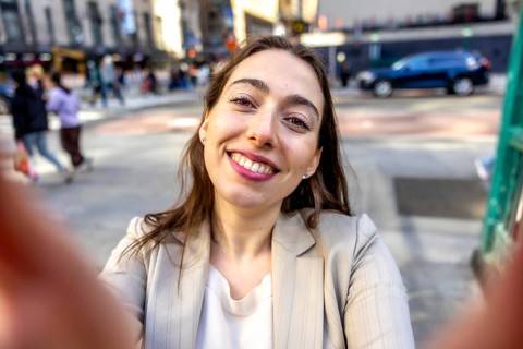 Young woman smiling into the camera for a selfie while exploring manhattan, capturing a joyful,