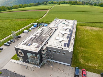 Modern building with solar cells on the roof in the midst of green fields, PV assembly, Perrot