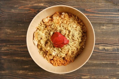 Bowl on wooden table filled with minced meat, boiled rice and spices. Red tomato sauce placed in