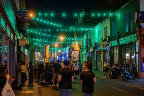 Street full of people under green fairy lights, reflecting the lively nightlife, nightlife, Dublin,