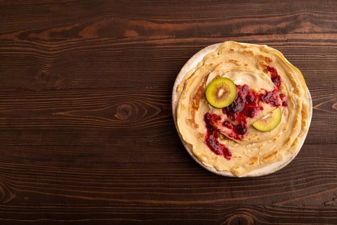 Stack of Plain Fried pancakes with jam and kiwi on brown wooden. top view, flat lay, copy space
