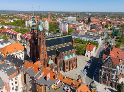Church with tall towers in an urban environment surrounded by buildings with red tiled roofs,