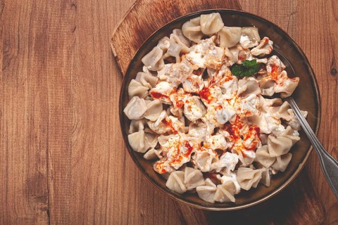 The dish features a generous serving of Turkish dumplings topped with velvety yogurt and a drizzle