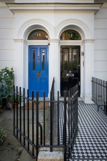 House entrances with blue and black front door, mosaic tiles and wrought iron fence in front of
