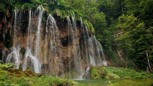 Majestic waterfalls flowing over mossy stones and rocks, Plitvice Lakes National Park, Croatia
