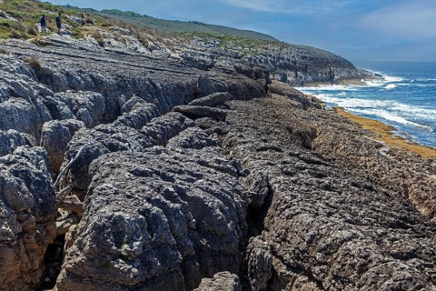A couple of hikers walk by San Vicente cliffs along the coast trail near San Vicente de la