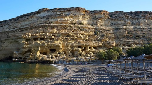 Neolithic caves, former hippie paradise, sandy beach with impressive rocks and empty umbrellas