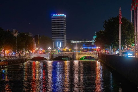 Nocturnal shot of an illuminated bridge with reflection in the river in an urban landscape,