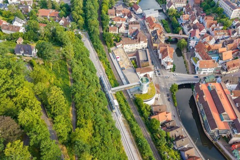 Cityscape with river and bridge, surrounded by railway tracks and urban structures in green nature,