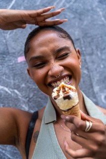 Happy young woman eating an ice cream cone with great delight, expressing pure joy and refreshment