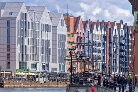 Tourists on the harbor promenade in front of a row of houses on the Motlawa in the port district of