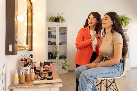Makeup artist and client share a joyful moment and laugh together after a completed makeup session