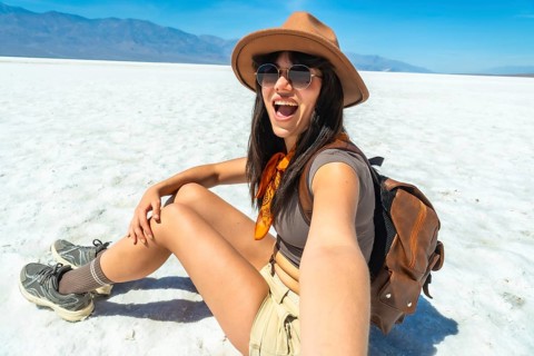 Woman backpacker sitting on the bright white salt flats of badwater basin in death valley national