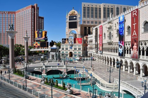 Venetian style architecture in Las Vegas with canals and bridges surrounded by billboards and